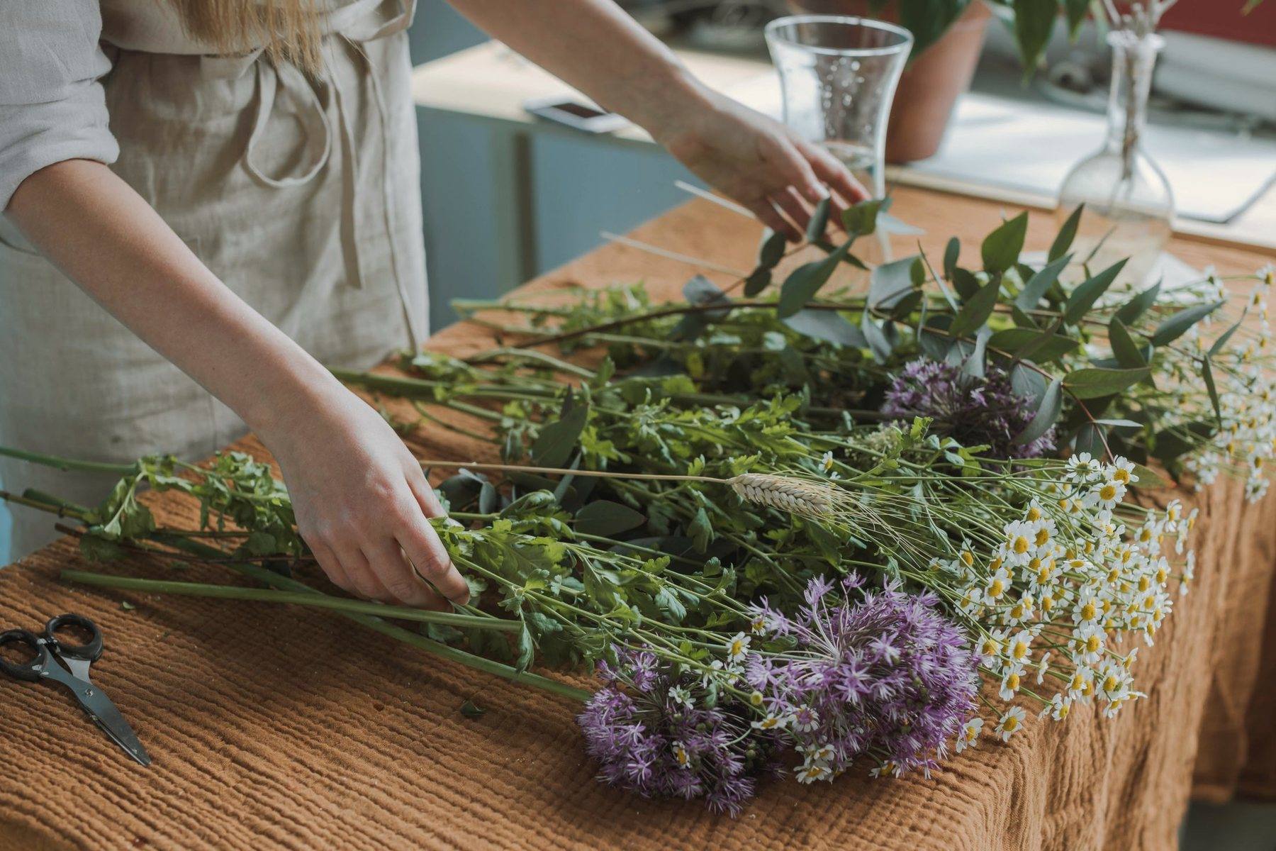 Stems of greenery and lavender laid out on a long wooden table