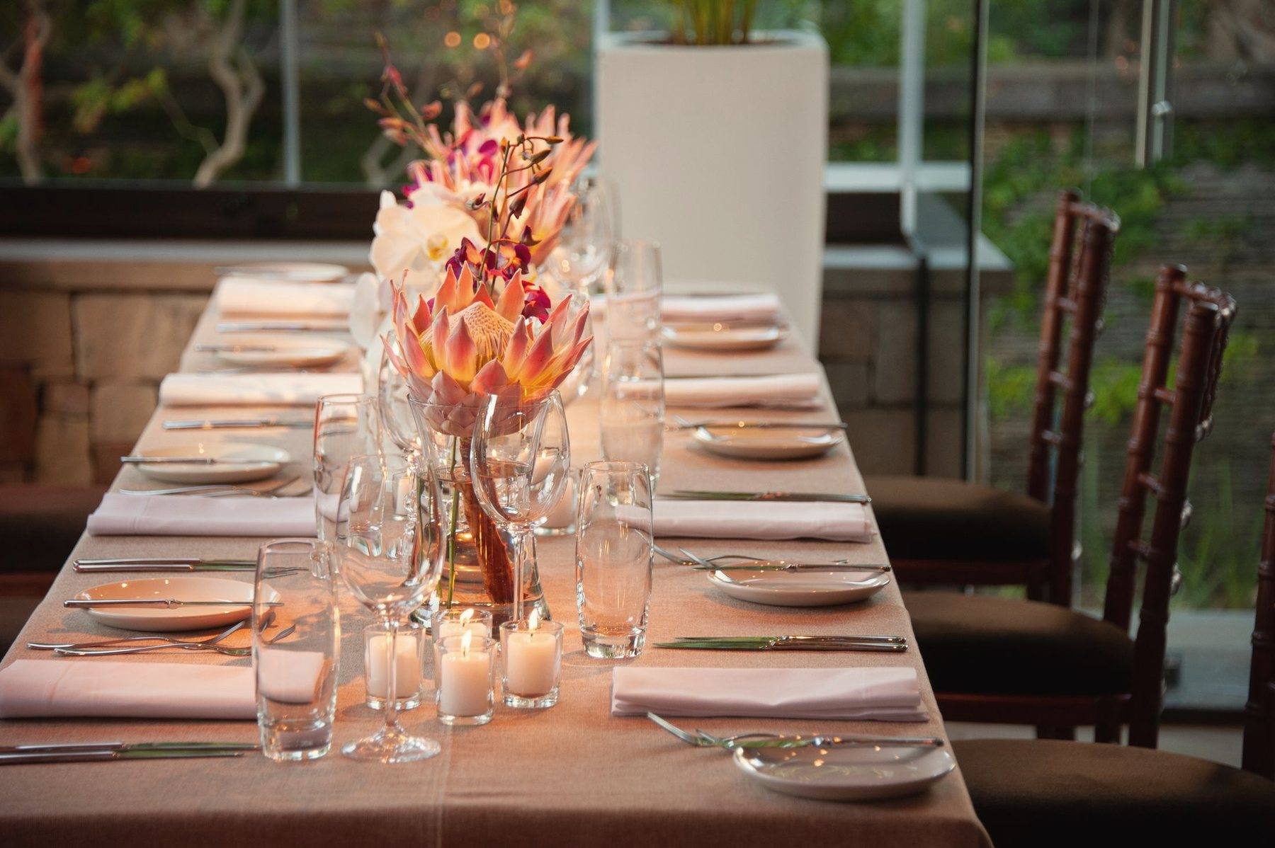 A long candlelit dinner table with a tall floral centrepiece
