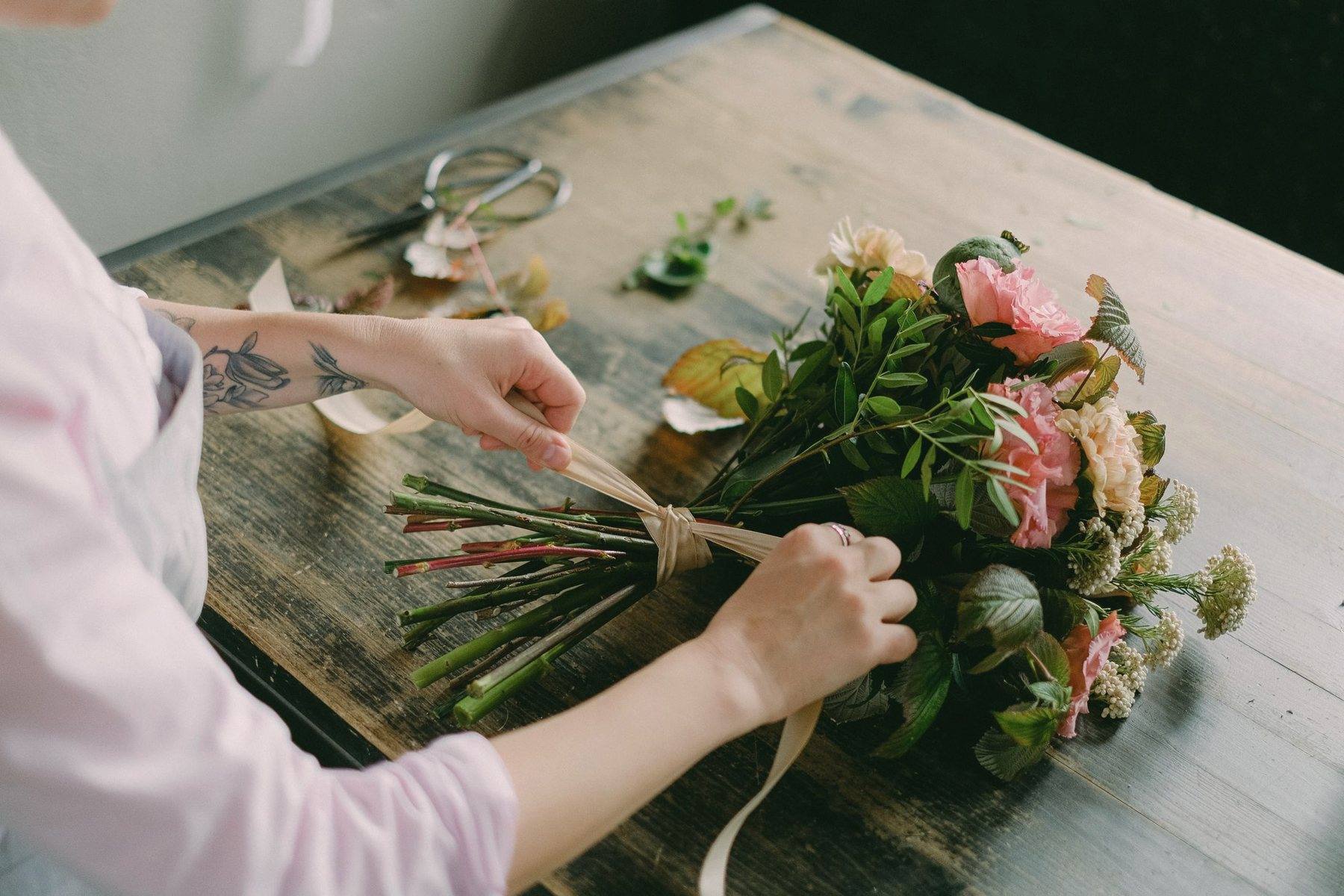 Hands tying a finished bouquet with ribbon